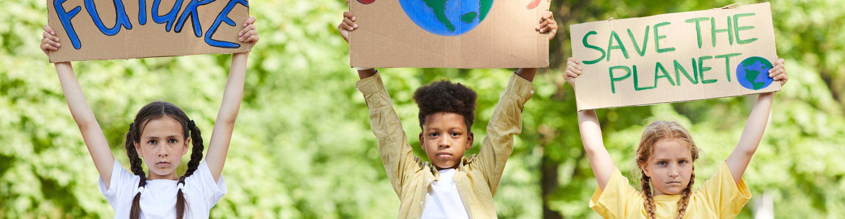 três crianças segurando cartazes com os dizeres: salve o futuro, um só planeta e salve o planeta