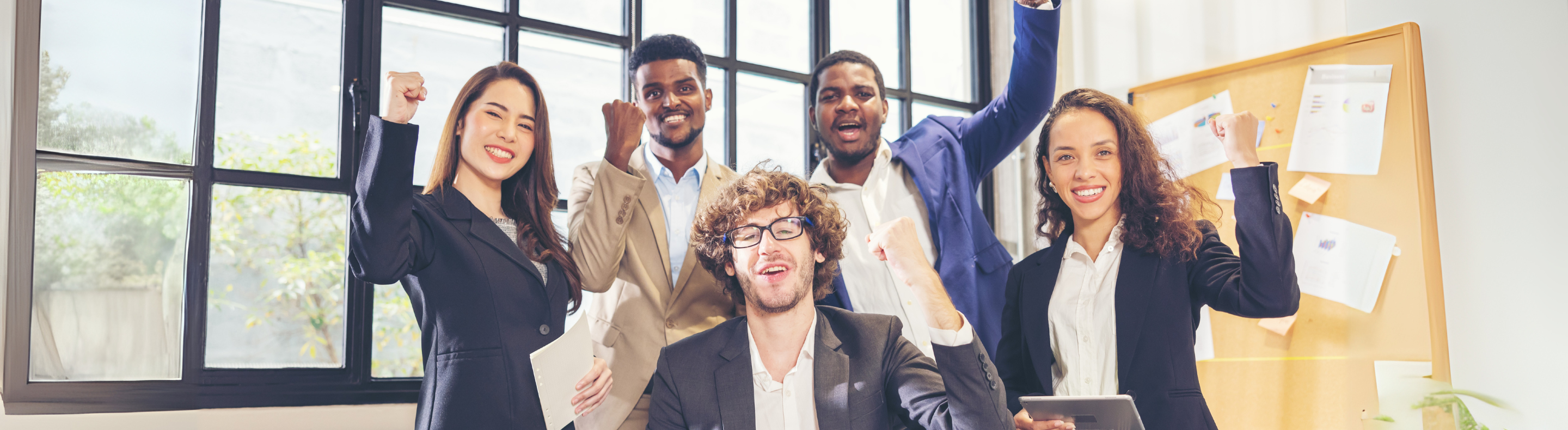 Foto de pessoas de diferentes etnias em ambiente corporativo em pose de comemoração