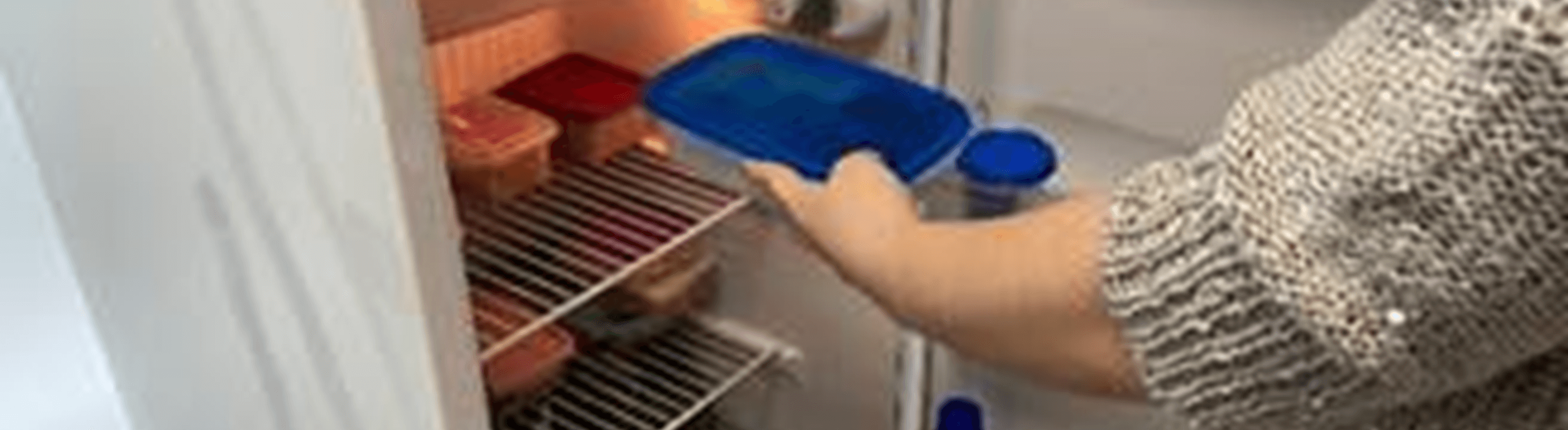 Uma pessoa colocando um pote na geladeira